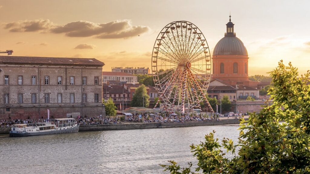 Best Things to See in Toulouse A picturesque view of Toulouse’s historic buildings and the Garonne River in France.