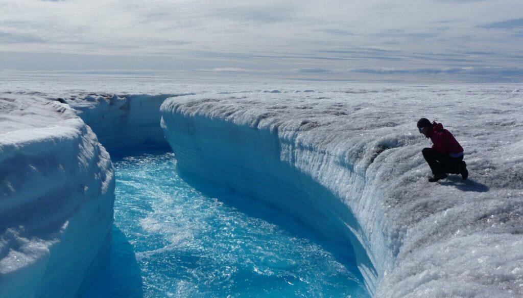 Scenic view of Greenland with massive icebergs, snowy mountains, and Arctic waters.